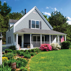 A beautiful American home with a green front yard and flower bushes on a sunny day